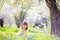 Cute little girl with curly hair wearing bunny ears and summer dress having fun during Easter egg hunt relaxing in the garden