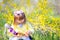 Cute little girl with curly hair wearing bunny ears and summer dress having fun during Easter egg hunt relaxing in the garden