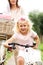 Cute little girl cycling in park with mother in background