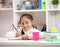 Cute little girl doing homework reading a book coloring pages writing and painting. Children paint. Kids
