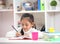 Cute little girl doing homework reading a book coloring pages writing and painting. Children paint. Kids draw. Preschooler with b