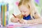 Cute little girl drawing with colorful pencils at a daycare. Creative kid painting at school