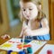Cute little girl is drawing with paints