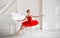 A cute little girl dreams of becoming a professional ballerina. In a white room, next to a piano, a girl in a bright red tutu is