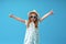 Cute little girl in a dress, hat and sunglasses poses on a blue background