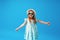 Cute little girl in a dress, hat and sunglasses poses on a blue background