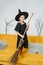 Cute little girl dressed as a witch holding a broom, posing for a photo