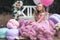 Cute little girl dressed in pink stunning dress holds French Macaron