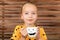 Cute little girl drinking pumpkin soup out of a cup with Halloween anthropomorphic smiley face. Halloween conceptual background.