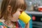 Cute little girl drinking warm milk from a yellow mug, close-up, side view. A hungry Baby is having breakfast at the dining table