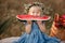 cute little girl eating big piece of watermelon on straw stack in summertime in the park. picnic with family. Adorable