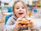 Cute little girl eating fast food in cafe