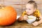 Cute little girl eating pumpkin soup and looking at a large Halloween pumpkin, with vicious face expression. Halloween.