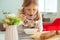 Cute little girl eating soup with whole grain bread at home