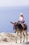 Cute little girl is enjoying her donkey ride by the ocean