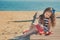 Cute little girl enjoying summer time on sea side beach happy playing with red star and tiny toy anchor on sand wearing nobby clot