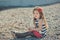 Cute little girl enjoying summer time on sea side beach happy playing with red star and tiny toy anchor on sand wearing nobby clot