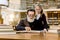 Cute little girl in eyeglasses at the table in ancient library, hugging her grandfather and reading book together