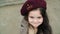 Cute little girl face in beret view from high angle. Portrait curly girl in beret looking to camera with embarrassed
