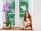 Cute little girl with flower sitting on windowsill of new pvc wi