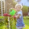 Cute little girl giving water garden flowers