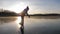 Cute little girl is going skate outdoors at sunset. A schoolgirl enjoying ice skating at frozen lake in winter season