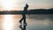 Cute little girl is going skate outdoors at sunset. A schoolgirl enjoying ice skating at frozen lake in winter season