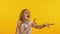 Cute little girl in good mood dancing on isolated orange background, slow-motion