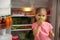 Cute little girl with green apple near open refrigerator