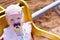 Cute little girl in hat with pacifier riding on carousel