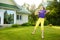 Cute little girl having fun on a grass on the backyard on sunny summer evening