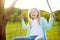 Cute little girl having fun on a swing outdoors in summer garden. Summer leisure for kids