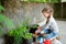 Cute little girl helping in a garden. Child taking part in outdoor household chores