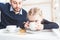 Cute little girl and her father drink tea with cookies at home.