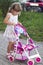 Cute little girl with her toy carriage and doll outdoors