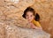 Cute little girl hides behind a rock
