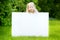 Cute little girl holding big blank whiteboard on sunny summer day outdoors