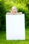 Cute little girl holding big blank whiteboard on sunny summer day outdoors