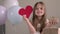 Cute little girl holding big red paper heart and zero waste gift on background of pastel colors air balloons. Valentines