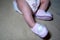 cute little girl infant wearing pink knitted baby booties, child lying on bed