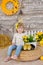 Cute little girl in jeans and white blouse playing hide and seek with a chicken sitting at a haystack close to yellow eggs and