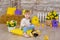 Cute little girl in jeans and white blouse playing hide and seek with a chicken sitting at a haystack close to yellow eggs and