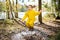 Cute little girl jumping in muddy puddle