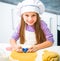 Cute little girl in the kitchen preparing cookies