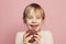 Cute little girl laughing and having fun with chocolate donut on pink color background