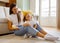 Cute little girl laughing while mother combing her hair at home