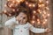 Cute little girl laying on flor with bright christmas garland in her hair. Christmas portrait, cozy style.