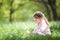 Cute little girl with mobile phone in the park. Family outdoor lifestyle. Happy small sitting on green grass. Beauty nature at