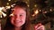 Cute little girl near Christmas tree branch with Bengal lights against the background of sparkling garlands. Happy Child