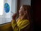 Cute little girl painting planet on window at home 4K. Happy Earth Day April 22 greeting message.Creative family leisure